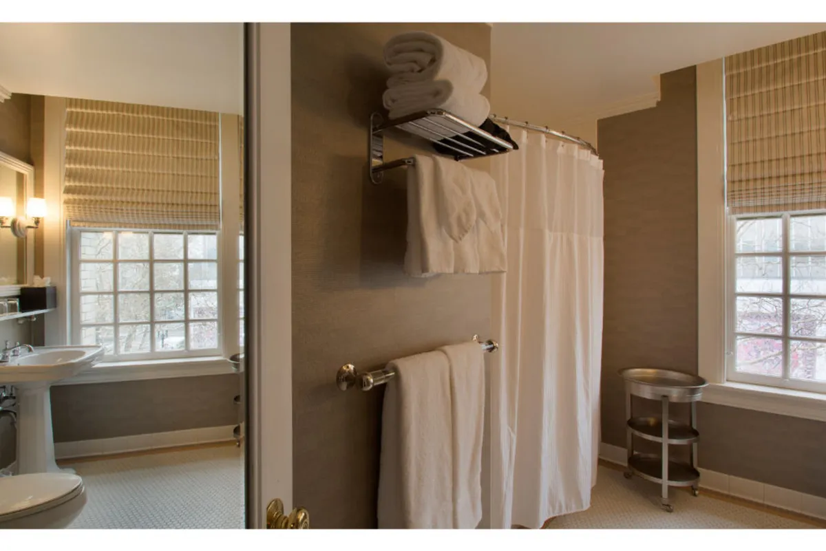 This image captures a serene bathroom featuring a shower curtain, neatly folded towels, a clean sink, and a window that lets in soft natural light. The composition evokes a sense of calm and self-care, emphasizing the core bathing experience.